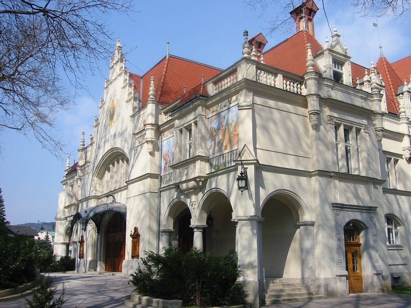 Prunkvolle, historische Fassade des Stadttheaters Berndorf mit verzierten Giebeln, Rundbogen-Arkaden und farbigen Wandfresken.